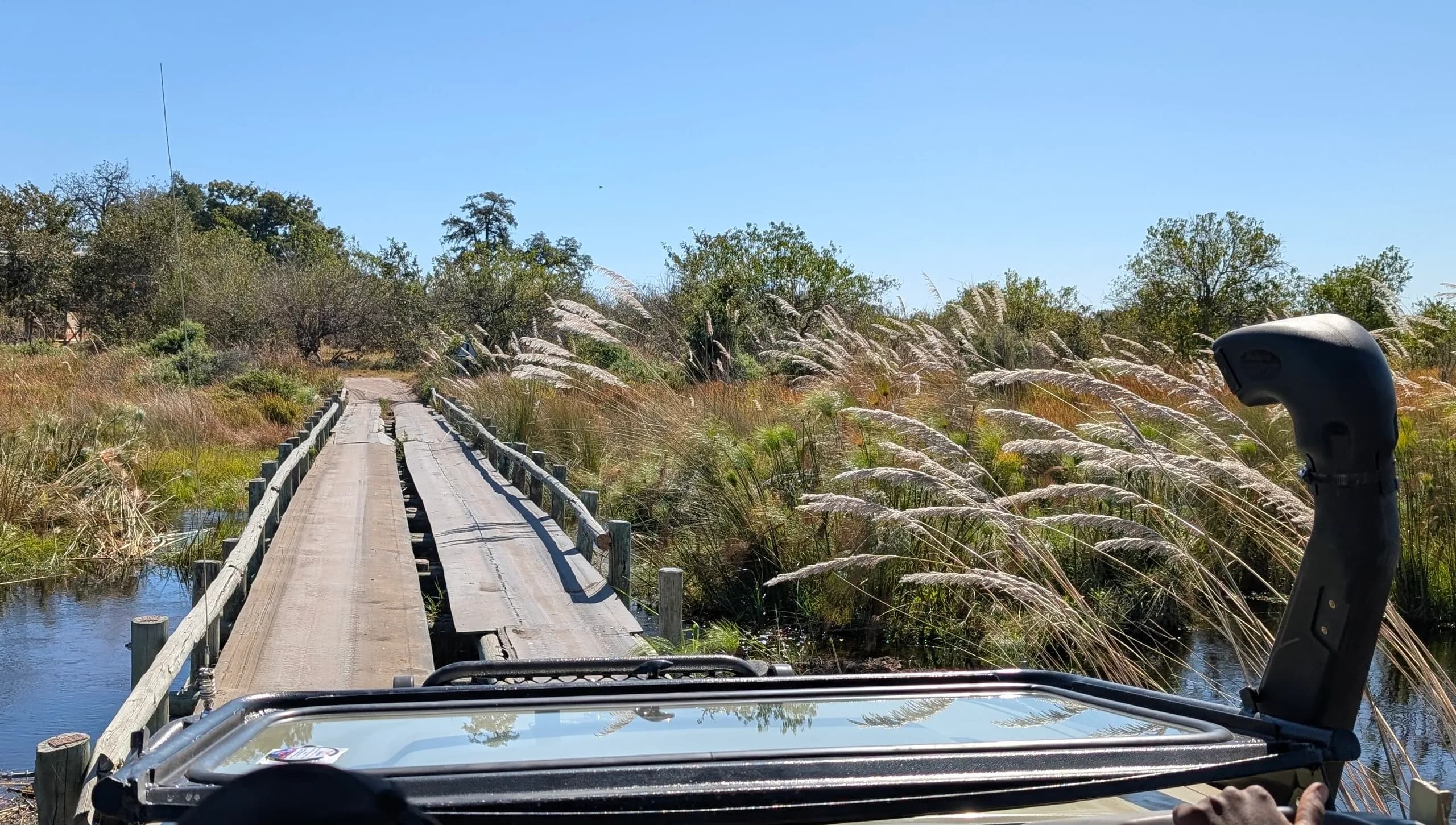 Safari vehicle crossing a wooden bridge in the Okavango Delta