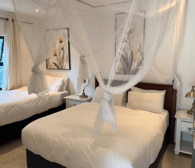 Twin bed room with mosquito net canopies at Bayete Guest Lodge